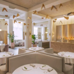 Elegant interior of Odette restaurant at National Gallery Singapore featuring minimalist round tables, soft pastel décor, and artistic ceiling mobiles — fine dining in a modern French setting.