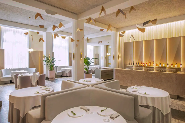 Elegant interior of Odette restaurant at National Gallery Singapore featuring minimalist round tables, soft pastel décor, and artistic ceiling mobiles — fine dining in a modern French setting.
