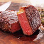 Juicy medium‑rare steak with seared crust on wooden cutting board beside knife and thyme — premium beef cooked to perfection.
