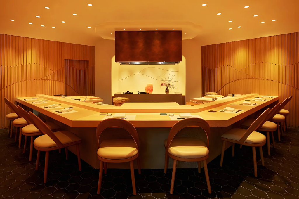 Elegant omakase restaurant with U‑shaped wooden counter, ambient lighting, and refined Japanese design in Singapore.