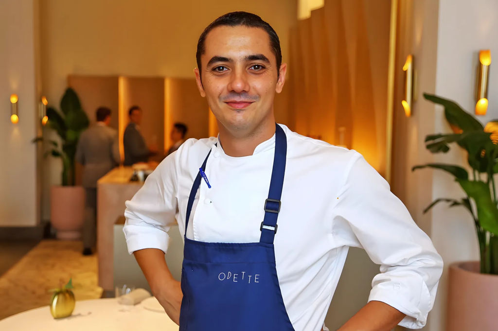 Chef Julien Royer wearing Odette apron inside his Michelin‑starred restaurant at National Gallery Singapore — renowned French fine dining chef in Singapore.