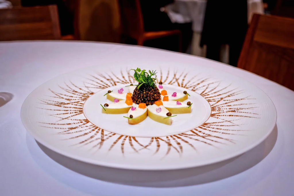 Beautifully arranged caviar and fruit dish with artistic plating and edible flowers at Les Amis Singapore, emphasizing fine dining elegance and creative French gastronomy.
