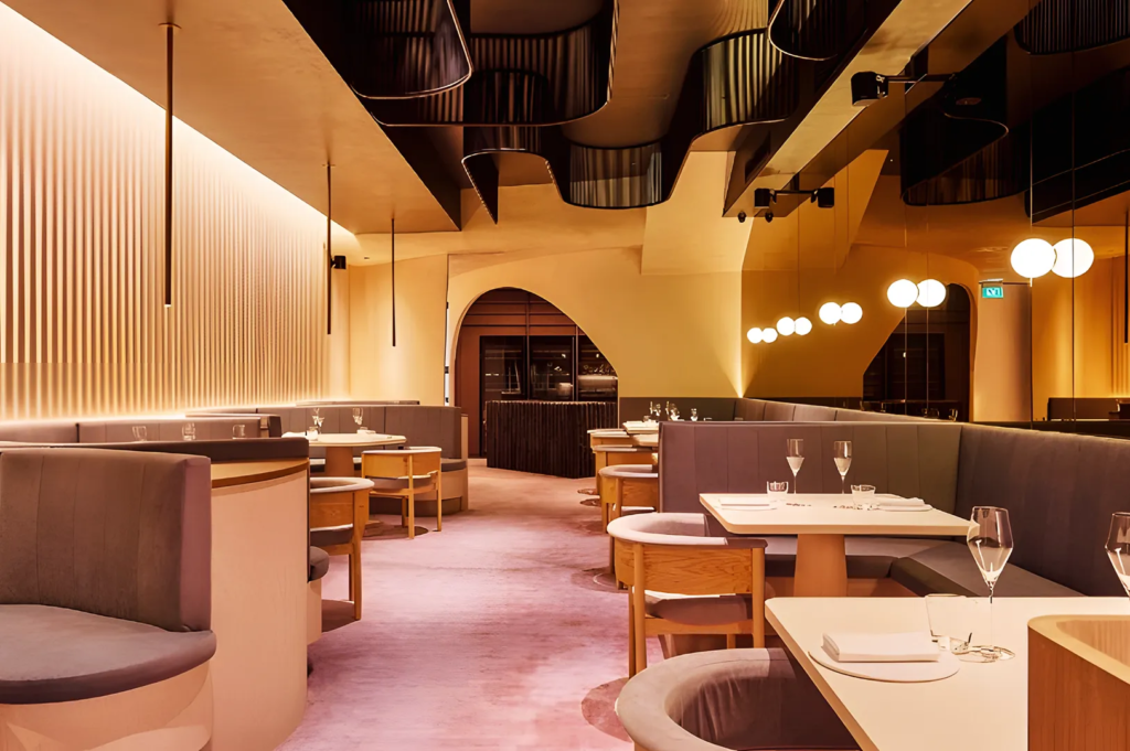 Luxurious Singapore restaurant interior with curved booths, soft lighting, and sculptural ceiling design creating an inviting fine‑dining atmosphere.