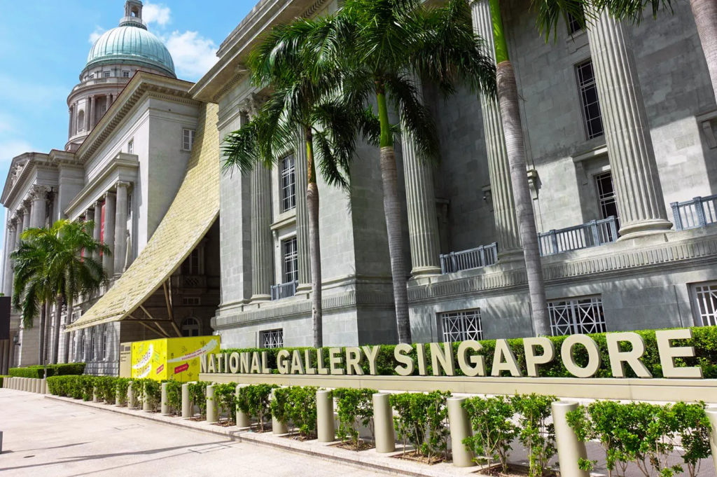 Historic façade of National Gallery Singapore with neoclassical columns, dome, and palm trees — iconic art museum housing Odette restaurant.