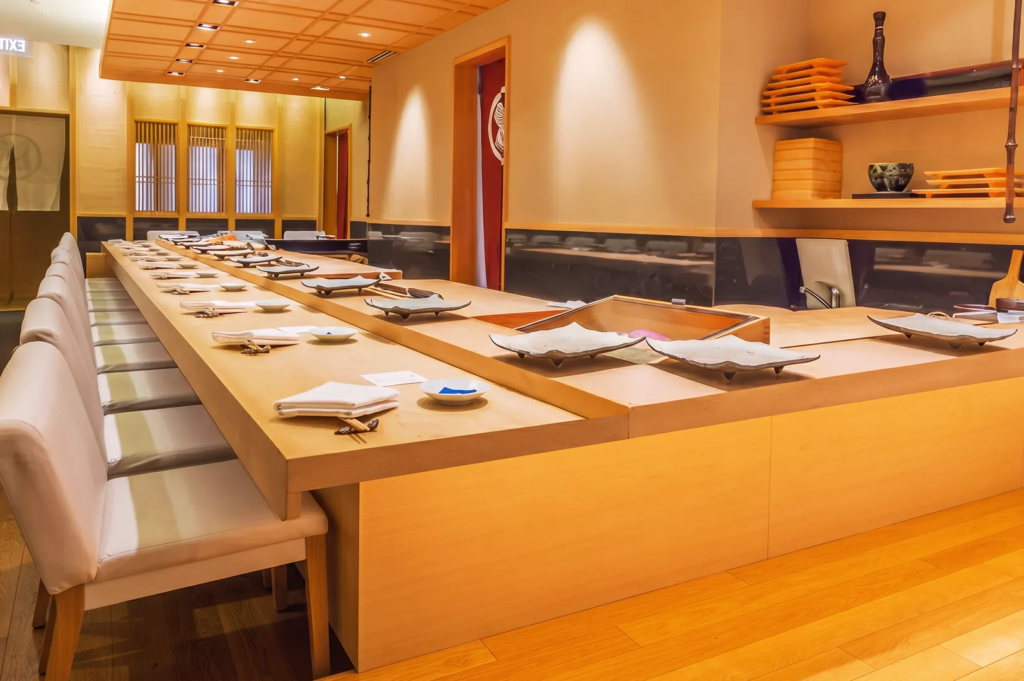 Classic Japanese sushi bar interior with wooden counter, ceramic plates, and minimalist décor for omakase dining.