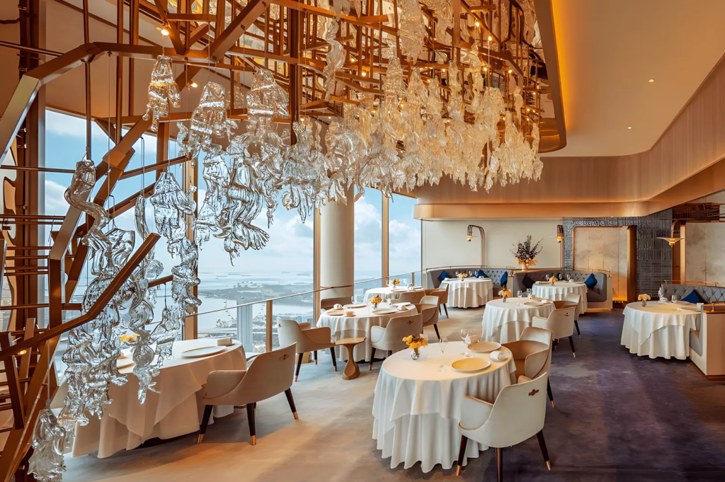 Luxurious restaurant interior with glass art installation and panoramic city view — contemporary fine dining at Marina Bay Sands Singapore.