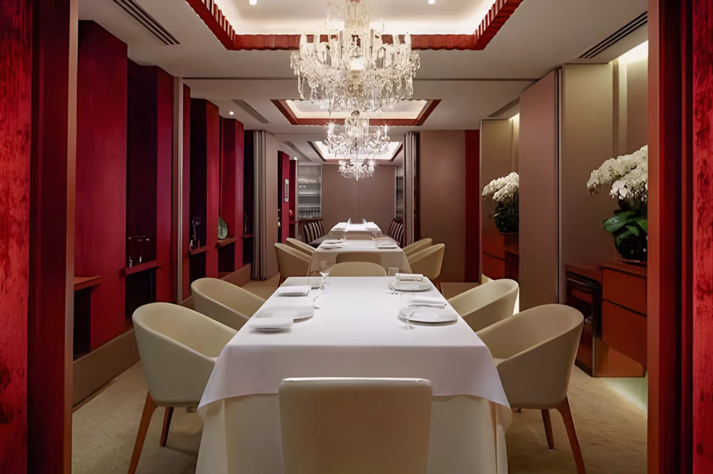 Elegant private dining room at Les Amis Singapore with crystal chandeliers, white tablecloths, and plush seating, designed for exclusive fine dining experiences.