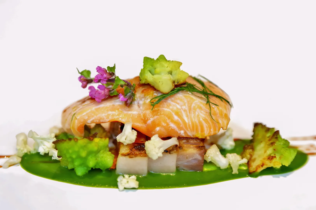 Beautifully plated salmon with Romanesco broccoli, cauliflower, and edible flowers — fine dining seafood creation at Odette restaurant Singapore.