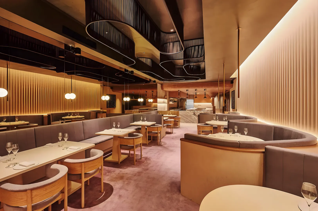 Stylish restaurant interior featuring curved booth seating, ambient lighting, and sculptural ceiling design, offering a cozy yet luxurious dining experience.