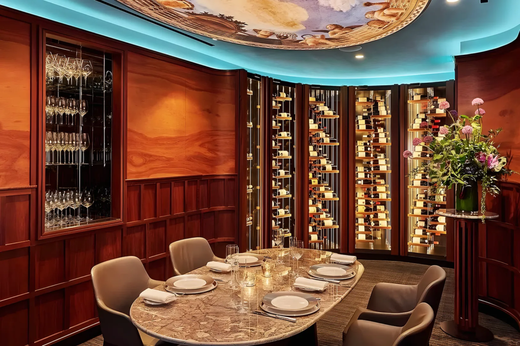 Luxurious wine cellar dining room at Les Amis Singapore with marble table, curated wine collection, and ceiling mural, offering an intimate and refined dining setting.