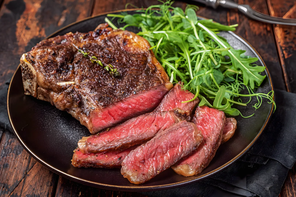 Sliced wagyu steak cooked medium‑rare, paired with fresh arugula on a dark plate; rich flavor and vibrant plating.