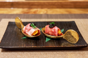 A5 Wagyu beef and uni sea urchin topped with black caviar on gold tasting spoons.