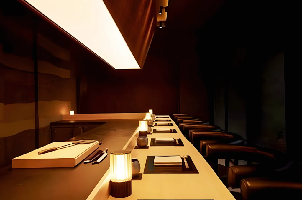 Modern sushi counter with ambient lighting and minimalist design, set for an intimate omakase dining experience in a high‑end Japanese restaurant.