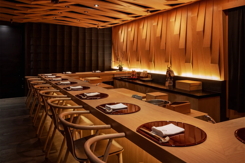 Modern Japanese omakase restaurant interior with wooden counter seating, warm lighting, and minimalist design — luxury sushi dining atmosphere.