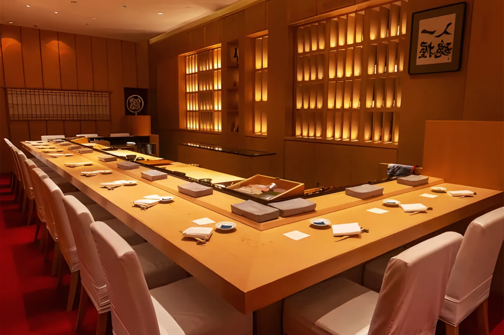 Interior of Shinji Japanese restaurant in Singapore featuring a warm‑lit omakase counter with minimalist wooden design and elegant seating.